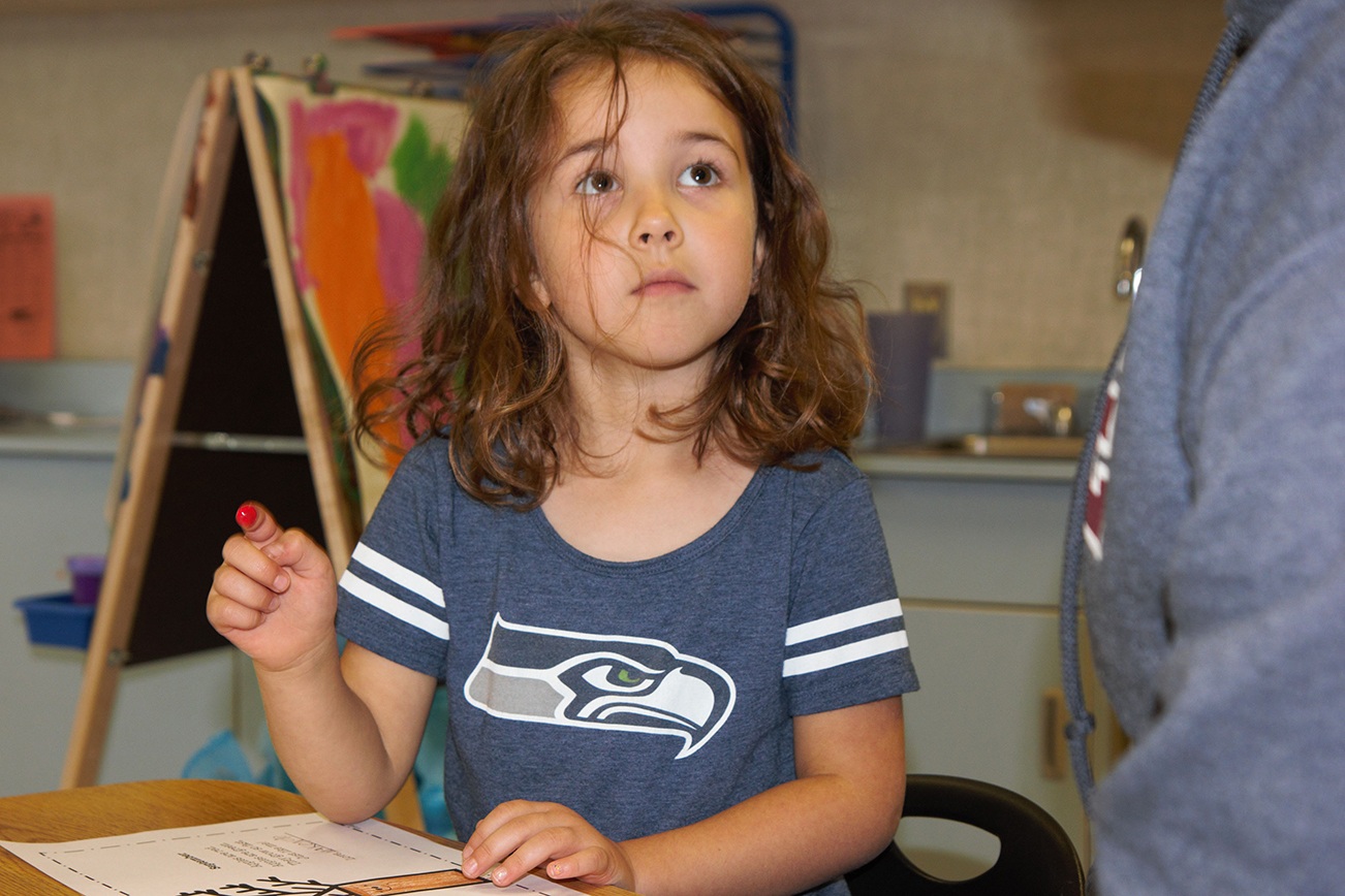 (Stephanie Morton | The Vidette)                                Makenzie Hart uses her fingertip to paint red apples on a tree as part of an assignment in Ms. Cady’s kindergarten class on Friday.