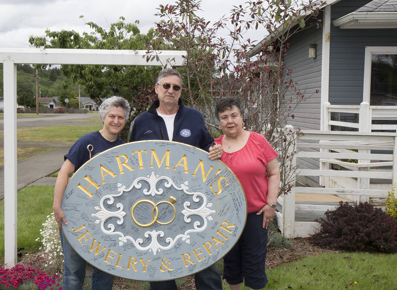 (Travis Rains | The Vidette) Ann Hartman (left), Tim Hartman (center) and Laurie Mansmith pose with the Hartman’s Jewelry and Repair sign that was signed with well-wishes and thanks from the community at a send-off event May 31.