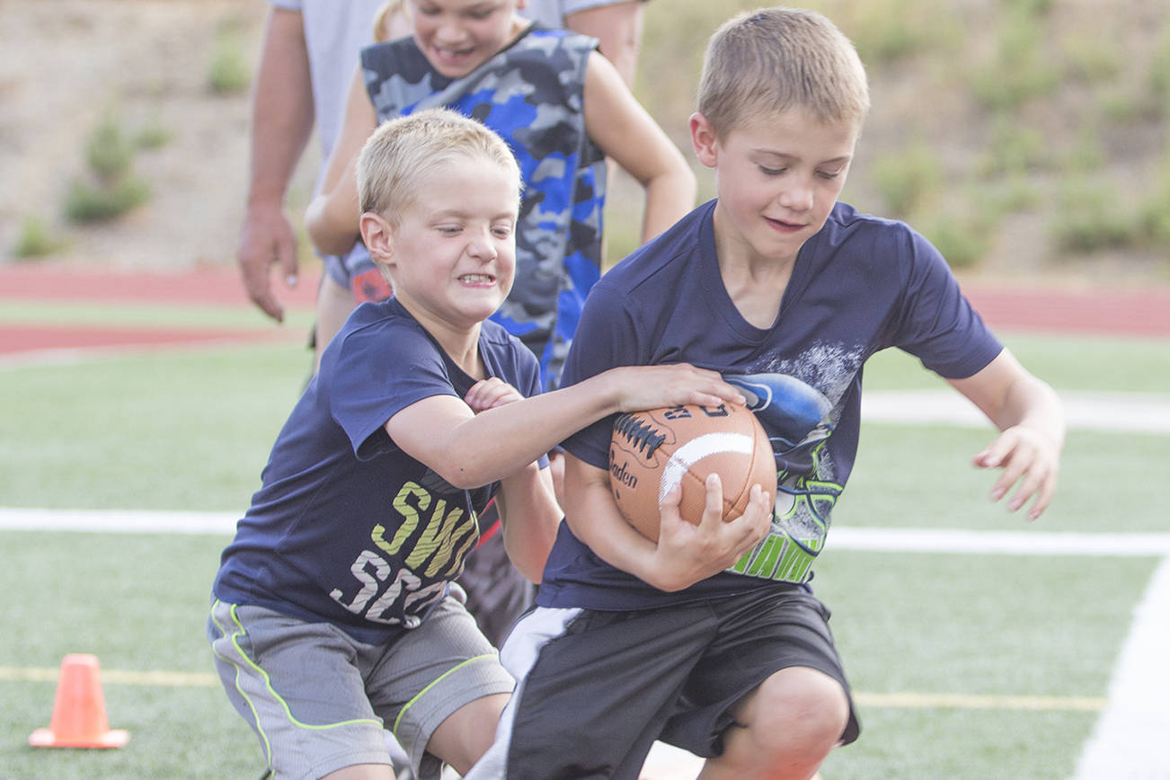 (Photo by Justin Damasiewicz) Andrew Bruland (left) tries to strip the ball from twin brother Peter Bruland during the Montesano Youth Football Camp on Monday at Rottle Field.