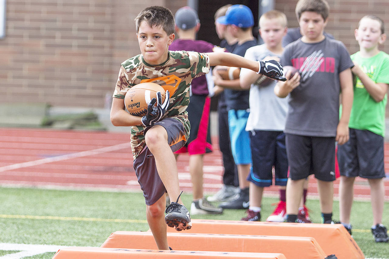 (Photo by Justin Damasiewicz) Daylon Schroeder high-steps over some bags during a ball-carrying drill at the Montesano Youth Football Camp on Monday at Rottle Field.