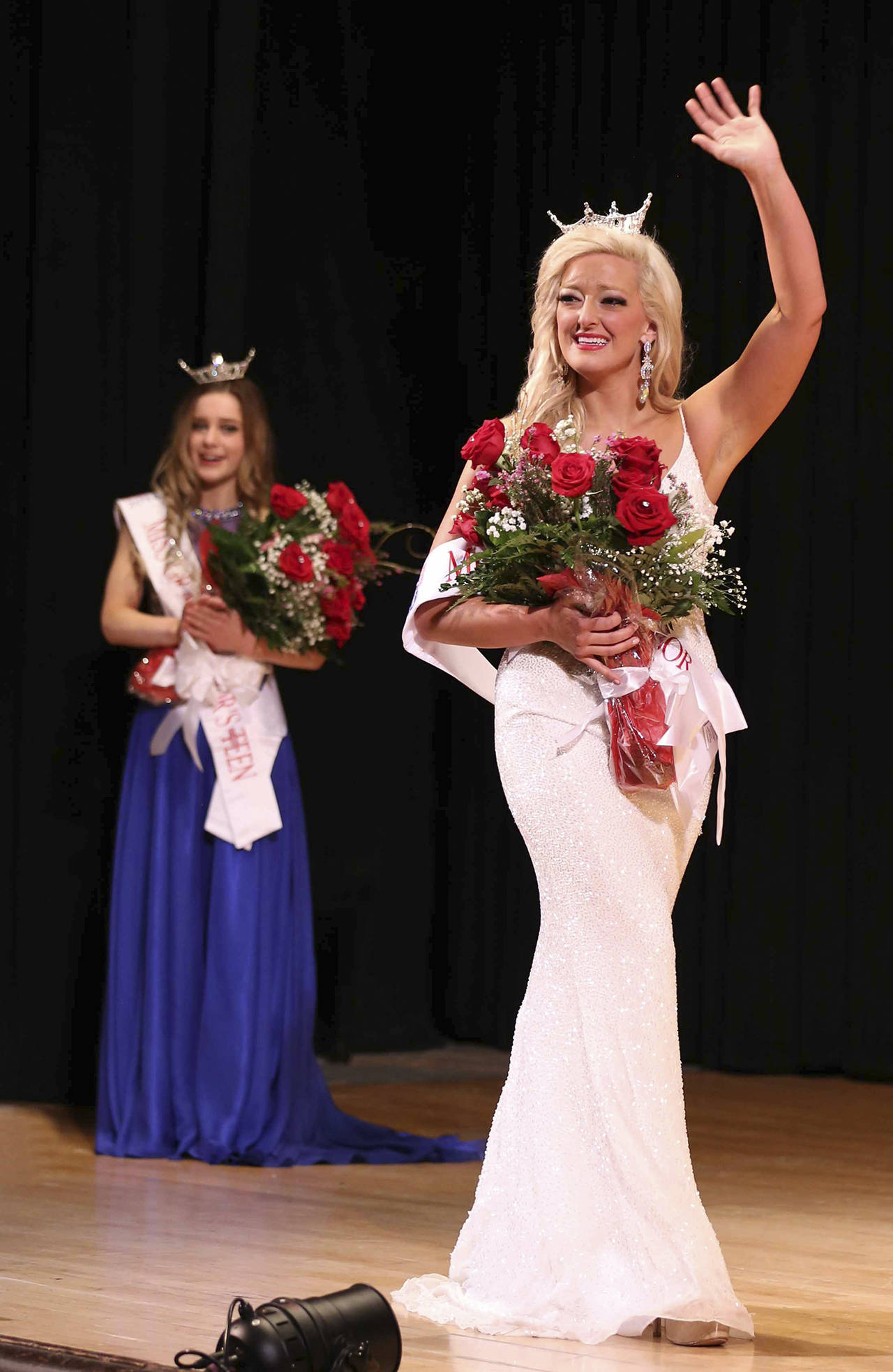 Photo by Keith J. Krueger                                Kuinn Karaffa, 22, waves after being crowned Miss Grays Harbor 2018 at the 7th Street Theatre in Hoquiam on Saturday. Behind her, at left, is Mercedes Morrill, 13, the newly crowned Grays Harbor Outstanding Teen 2018.