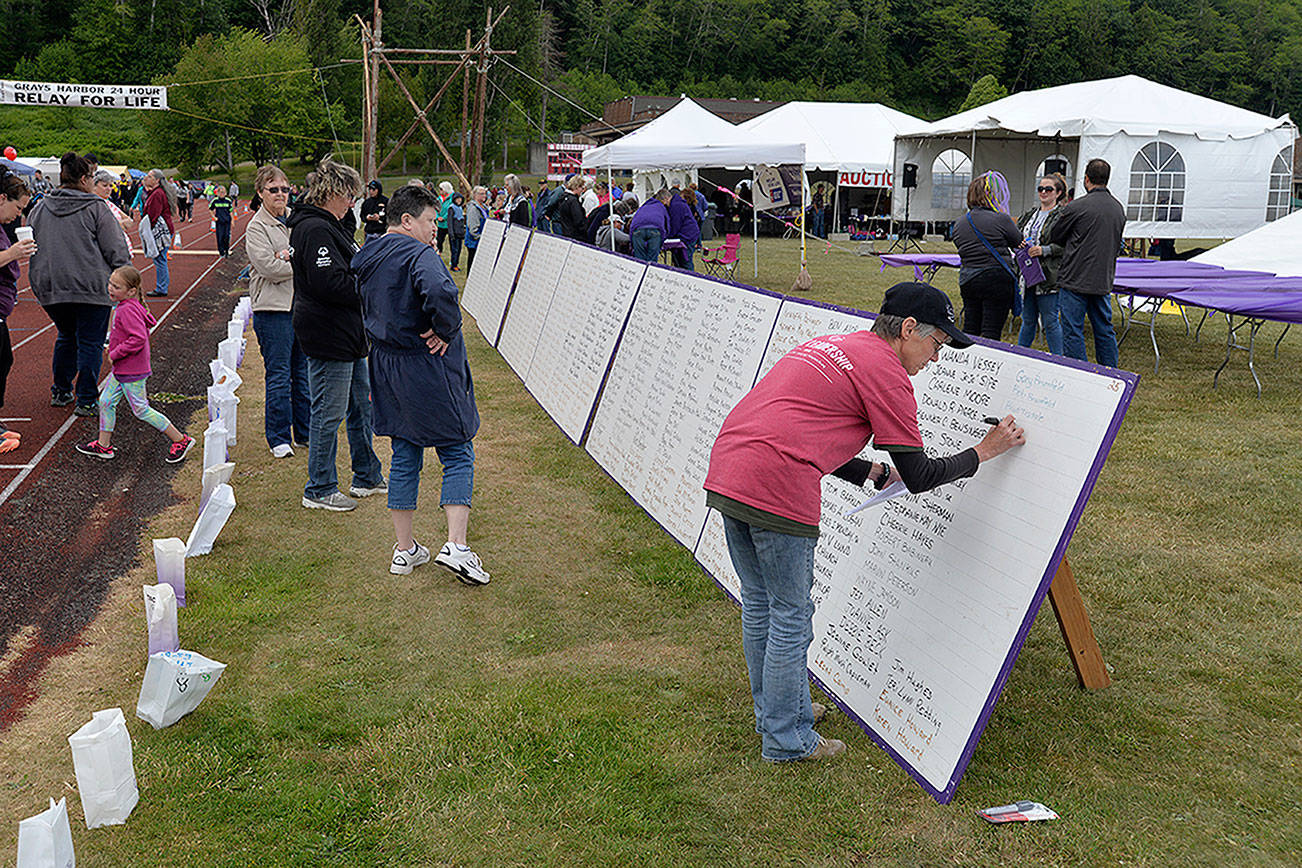 LOUIS KRAUSS | THE DAILY WORLD Someone writes names of those lost to cancer on a board at the Relay For Life in Hoquiam on Friday.
