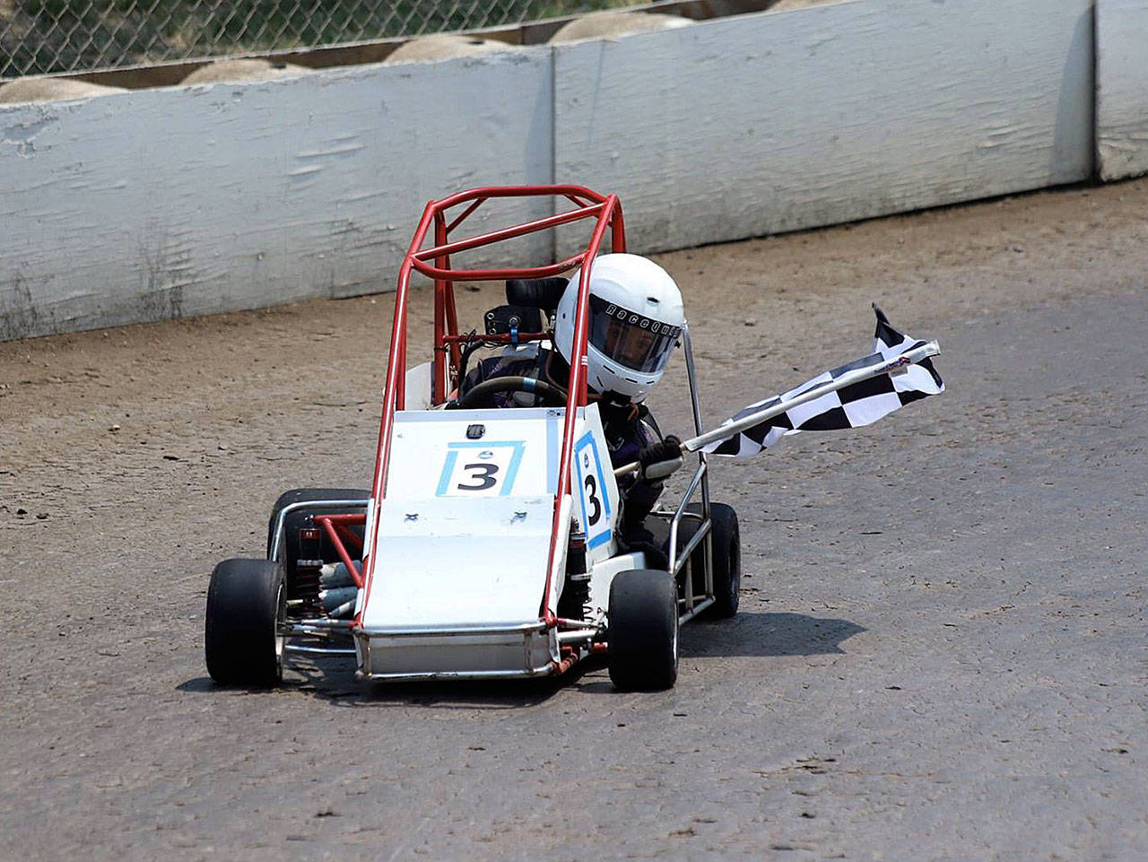 Grayden Youmans celebrates with the checkered flag after winning the Senior Novice event at the QMA Dirt Grand Nationals in California. (Photo by Steve Youmans)