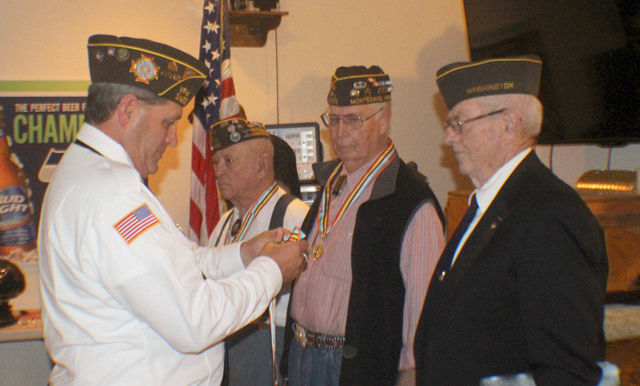 Photos by Michael Lang | The Vidette                                Above, Commander Kyle Winkle, from left, of the Veterans of Foreign Wars Post 2455 in Montesano, presents Ambassador For Peace medals to Korean War veterans Herb Beck of Montesano and Maurice Fox and Lloyd Jorgensen, both of Aberdeen, during a ceremony Aug. 21, 2018, at the VFW hall in Montesano. At left, Grand Edwards receives recognition for his 60-year membership at the VFW from Winkle. Edwards is believed to be the oldest veteran in the county. At right is the Ambassador For Peace medal.