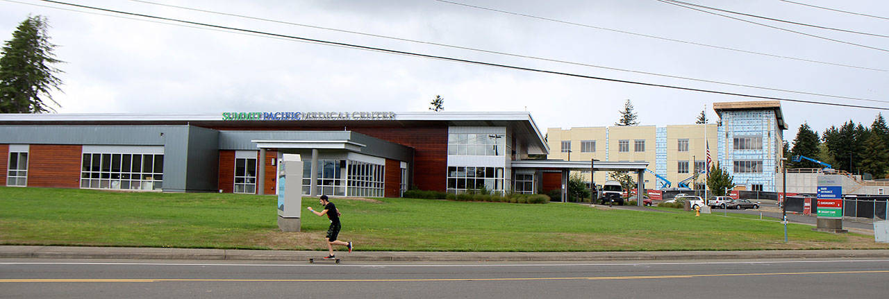 A skateboarder passes Summit Pacific Medical Center, where the new Wellness Center, right, begins to take shape behind the hospital Thursday, Aug. 30, 2018, in Elma. Photo by Michael Lang, The Vidette