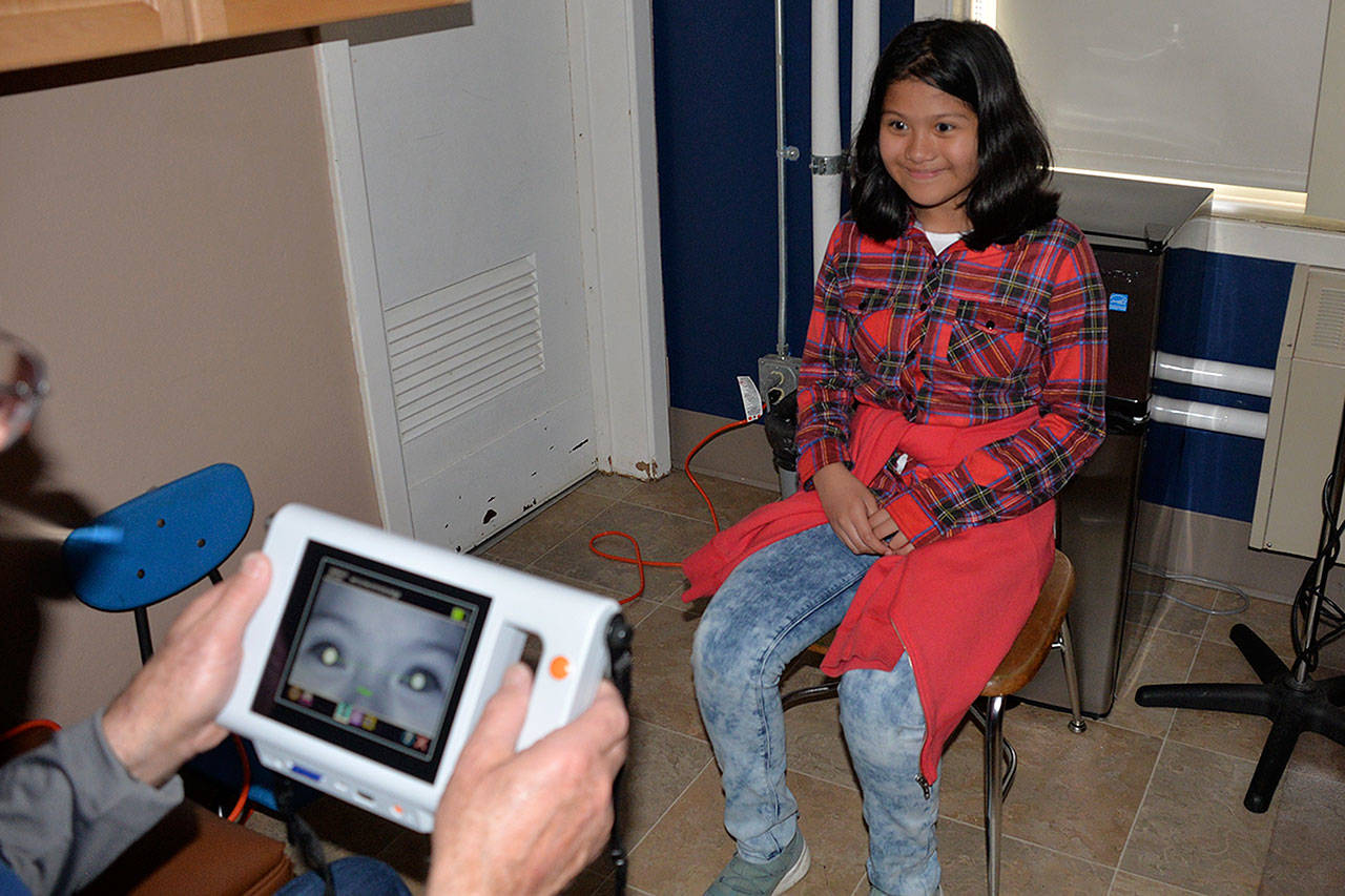 Louis Krauss | The Daily World                                Stevens Elementary student Arianna Alavez gets her eyes examined by Erv Granahan on Thursday.