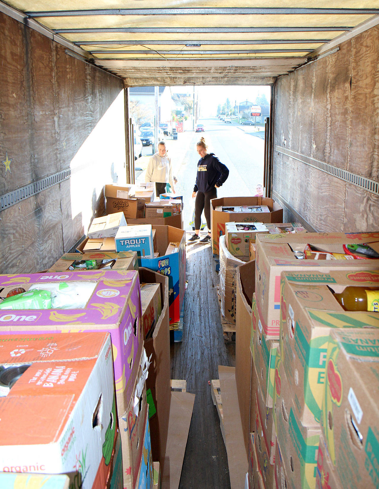 Montesano High School sophomore Cassadie Golding, left, and Katie Granstrom, a senior, examine the load of food collected for the school’s Food Bowl activities and held in a trailer on Monday, Dec. 3, 2018, in Montesano.