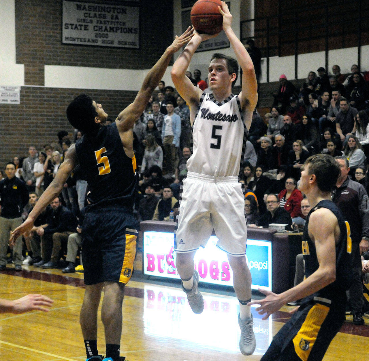 Montesanos Evan Bates, middle, hits a shot while defended by Javier Bojorge in the fourth quarter of a game on Friday. (Hasani Grayson | Grays Harbor News Group)