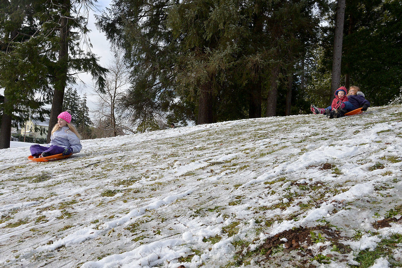 (Louis Krauss | Grays Harbor News Group) From left, Lila Erickson, Kendlynn Garmin and Deacon McCracken sled down a hill at Sam Benn Park Monday morning.