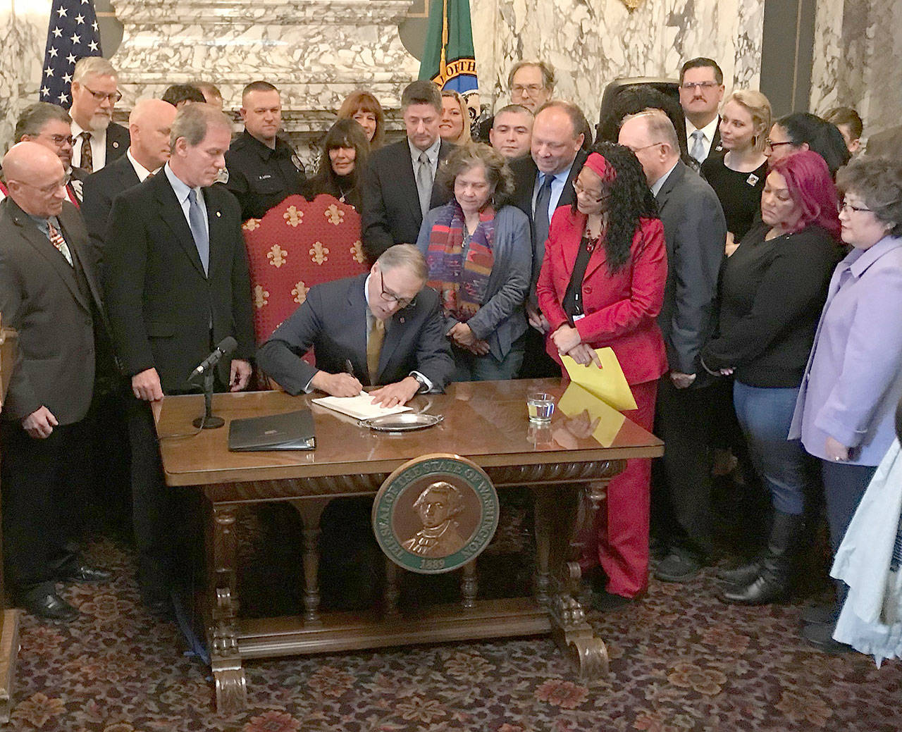 Washington Gov. Jay Inslee signs the first bill of the 2019 legislative session Monday, Feb. 4, at a ceremony in the State Reception Room in Olympia. Substitute House Bill 1064, adds training requirements for law enforcement officers to de-escalate situations and expands training in the areas of mental health and first aid to help avoid the use of deadly force. The law contains an emergency clause and takes effect immediately. “This bill which passed unanimously in both chambers doesn’t fix everything,” Inslee said. “Far from it. But it is a start and it is a message that when people listen to each other and open their hearts to each other, justice can move forward.” Photo by Sean Harding | Washington Newspaper Publishers Association