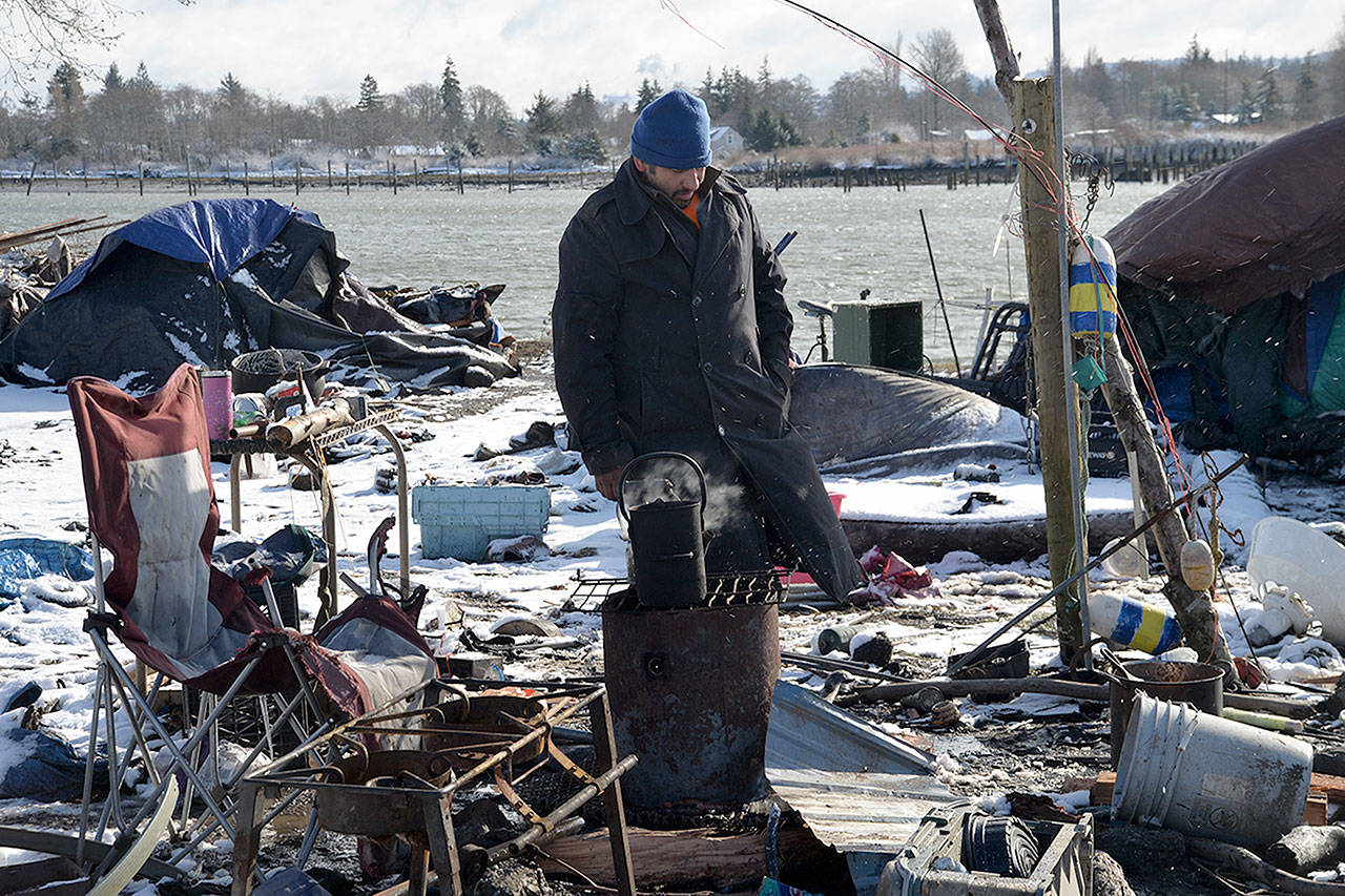 Louis Krauss | Grays Harbor News Group                                Leon Obi monitors a block of ice he’s melting in a pot for coffee and to melt bouillon cubes for soup. He said he couldn’t get any sleep in his van Friday night during a snowstorm.