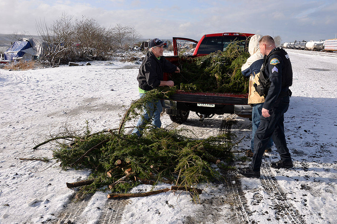 (Louis Krauss | Grays Harbor News Group) David Walsh, left, pulls tree branches out of his truck to give to homeless people along the Chehalis River in Aberdeen.