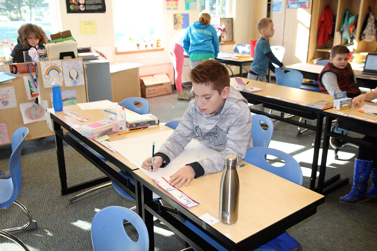 Colton Sweet adds pictures to his poster Wednesday, Feb. 6, in Emily Egger’s classroom at Simpson Elementary in Montesano. Egger’s class is leading a transformation at the school away from plastic utensils served with breakfast and lunch to using washable metal forks and knives.