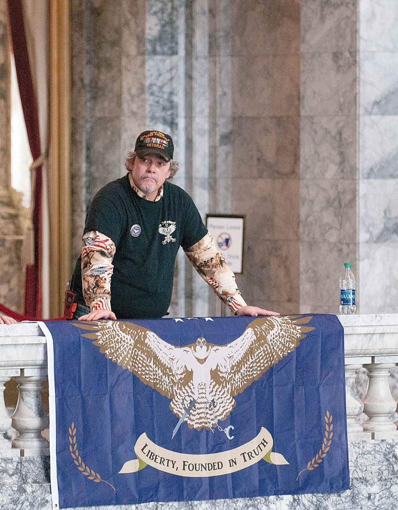 Robert Brown, an advocate for splitting Washington into two states, stands over a flag at a rally Feb. 15 at the Capitol in Olympia. — Photo by Sean Harding, Washington Newspaper Publishers Association