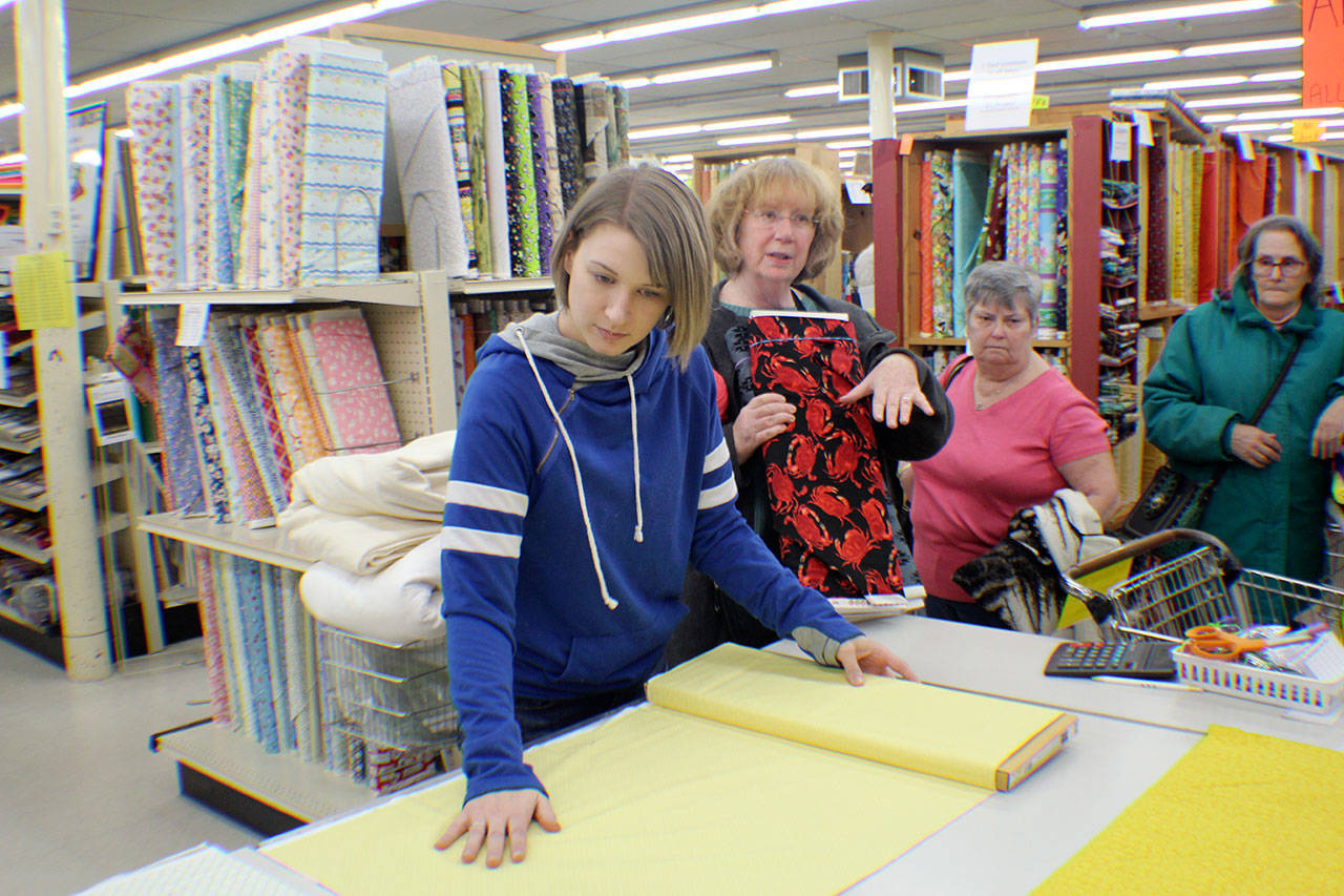 Chelsie Vogel cuts fabric at her grandmother’s store Friday, March 1, 2019, in Elma. Carol Morrow is selling Elma Variety Store, which she and her husband, Boyd, owned for more than 40 years. The customers started lining up early Friday for a liquidation sale. Michael Lang | Grays Harbor News Group