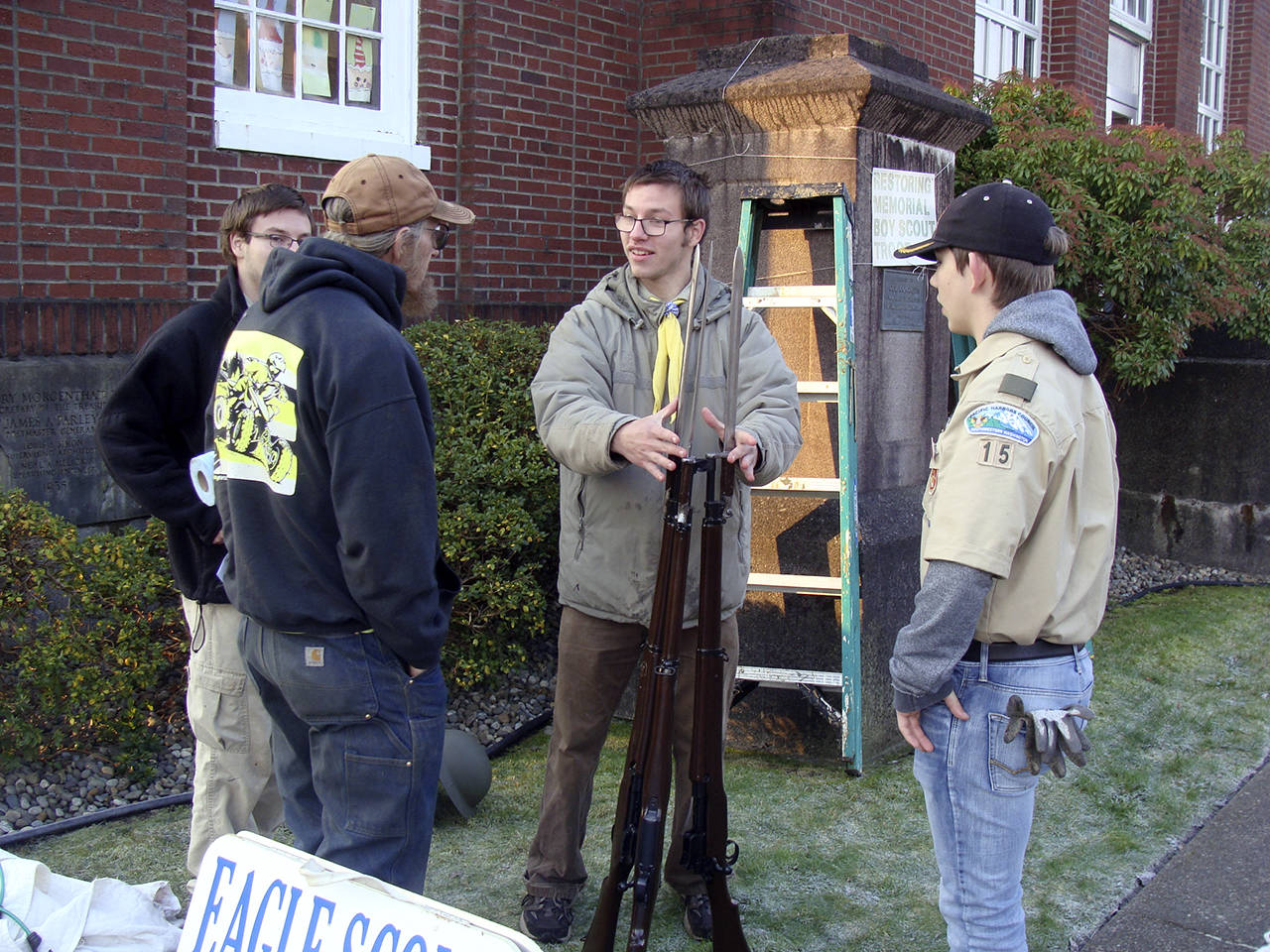 (Photo courtesy Malchert family) Joseph Malchert, center, talks with volunteers (including his twin, Daniel, far left) about mounting the rifle display at the World War I memorial in Montesano.