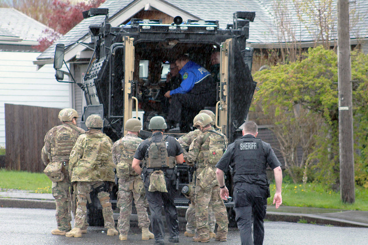 (Photo courtesy Josh Jessen) Officers in camouflage armed with rifles take up positions on the west and south sides of a Montesano home as a negotiator attempts to bring a suspect out of the residence on Tuesday.