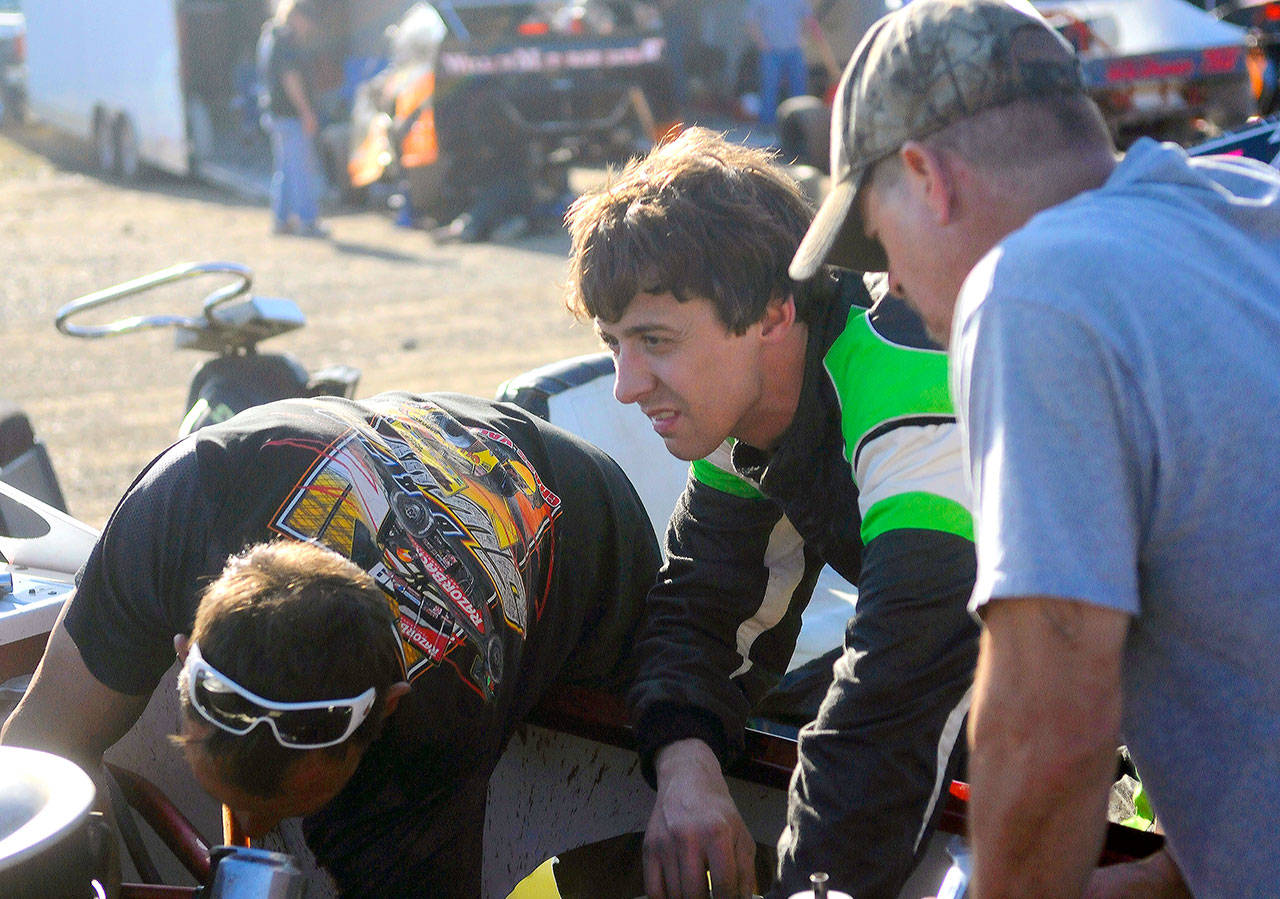 Pat Lamb, left, Zack Simpson, center, and Ray Jensen all work on the carburetor of Simpson’s street stock race car in between races at Grays Harbor Raceway on June 15. (Hasani Grayson | Grays Harbor News Group)