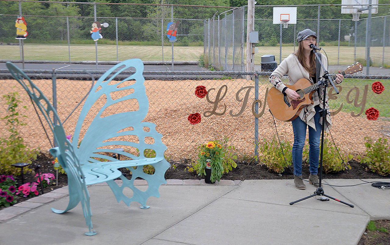 DAN HAMMOCK | GRAYS HARBOR NEWS GROUP                                Ericka Corban performs Wednesday at the Lindsey Baum remembrance garden dedication at Beerbower Park in McCleary. At left is the butterfly bench purchased by an anonymous donor.