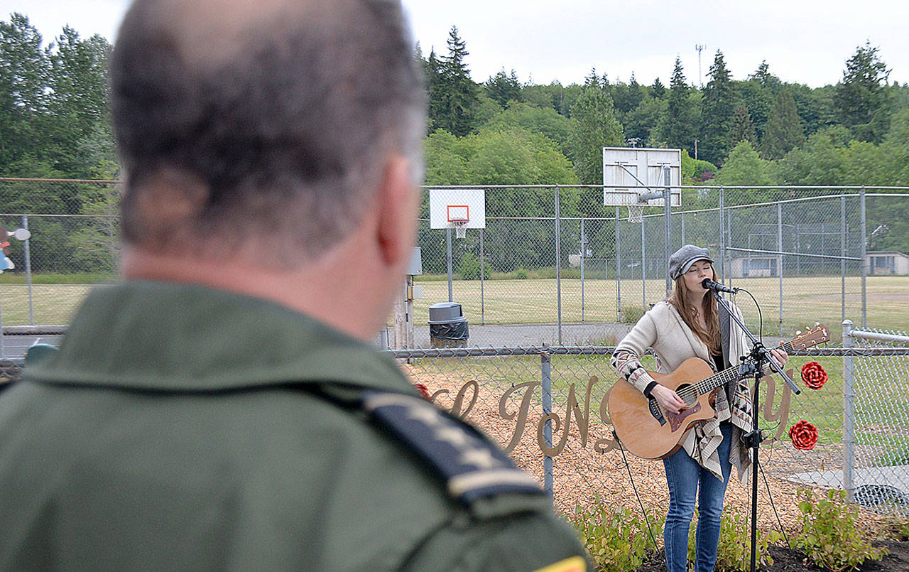 DAN HAMMOCK | GRAYS HARBOR NEWS GROUP                                Grays Harbor County Sheriff Rick Scott watches local singer/songwriter Ericka Corban perform “See You Again” at the Lindsey Baum remembrance garden dedication Wednesday in McCleary.
