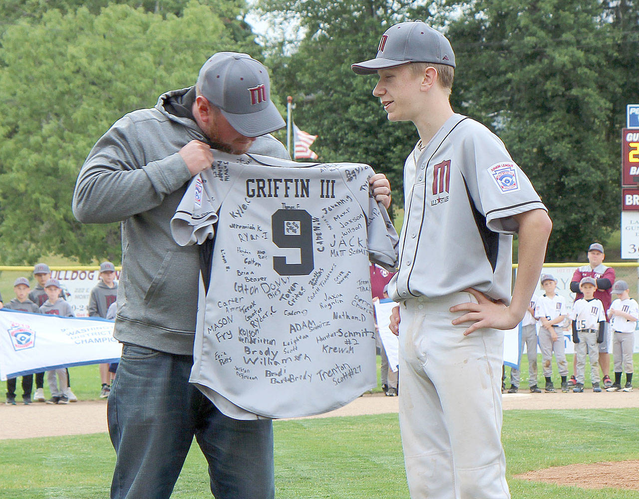 John Griffin (right) is presented a jersey autographed by fellow Little League baseball players.