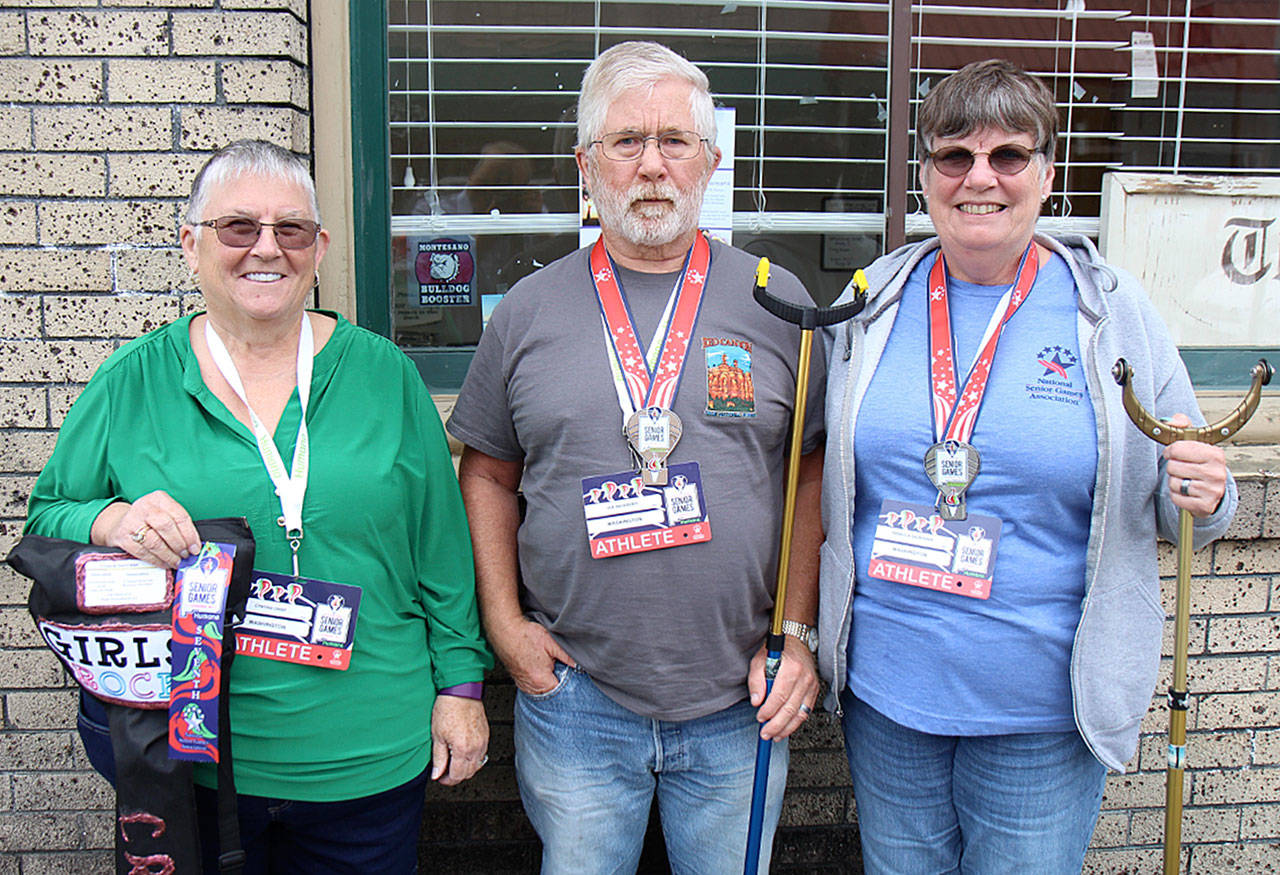 Montesano natives Cynthia Crisp (from left), Joe Sackrider and Becki Sackrider pose Tuesday, July 9 outside The Vidette offices in Montesano with their shuffleboard cues and awards. The trio recently returned from Albuquerque, New Mexico, where they placed in the National Senior Games for their age group. (Photo by Michael Lang | Grays Harbor News Group)