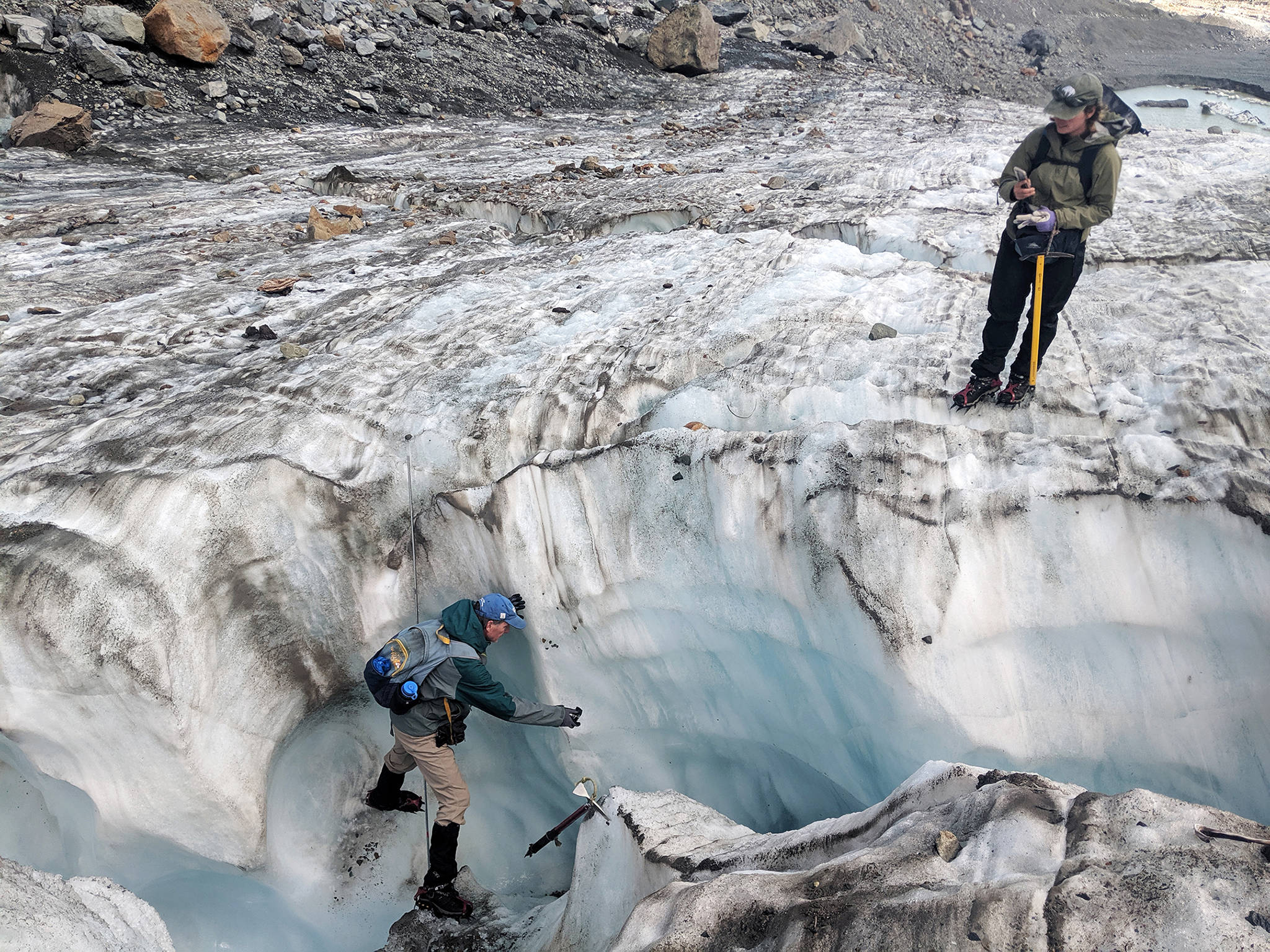 Taking a break from recording numbers, scientist Mauri Pelto balances on the walls of an ice chute to take footage of a water current on Columbia Glacier. (Zachariah Bryan / The Herald)