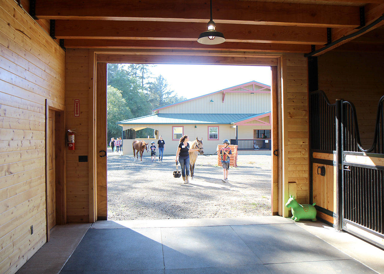 Visitors and volunteers lead horses back to the stables Monday, Aug. 26, 2019, at a farm north of Hoquiam during the Horse Prayer and Summit Pacific Medical Center event to introduce equine-assisted therapy to children with autism. (Michael Lang | Grays Harbor News Group)