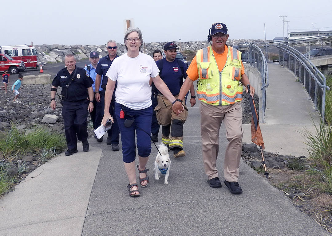 Kat Bryant | Grays Harbor News Group                                Charlcie Koster walks the final steps with Glenn from the Westport Observation Tower to the beach at Half Moon Bay. Pictured with them, from left, are Westport Police Cpl. Kevin Chaufty and, representing the South Beach Regional Fire Authority, EMR Chris Timm, Capt. Darin Vander Veur, firefighter/EMT Paul Barrow and Lt. Eric Delgado.