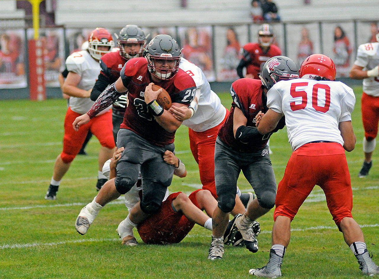 Hoquiam running back Matt Brown carries two would-be Castle Rock tacklers during the Grizzlies’ 48-12 victory over the Rockets at Olympic Stadium on Friday. (Ryan Sparks | Grays Harbor News Group)