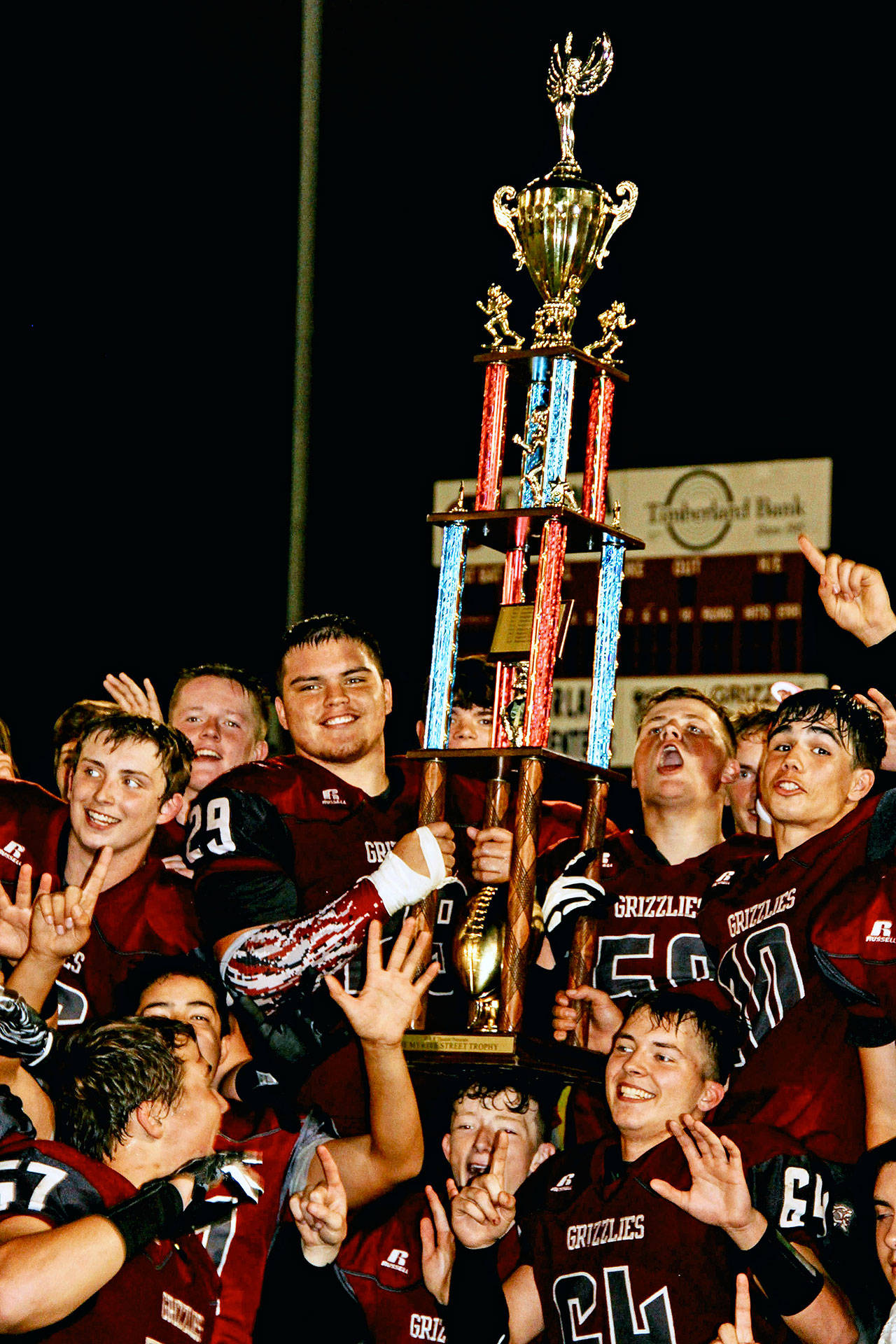 The Hoquiam Grizzlies hold up the Myrtle Street Rivalry trophy after defeating the Aberdeen Bobcats 56-3 on Friday, Sept. 13. Hoquiam has won 13 of its last 14 games dating back to last season and faces La Center on Friday. (Photo by Jinny Marchand)