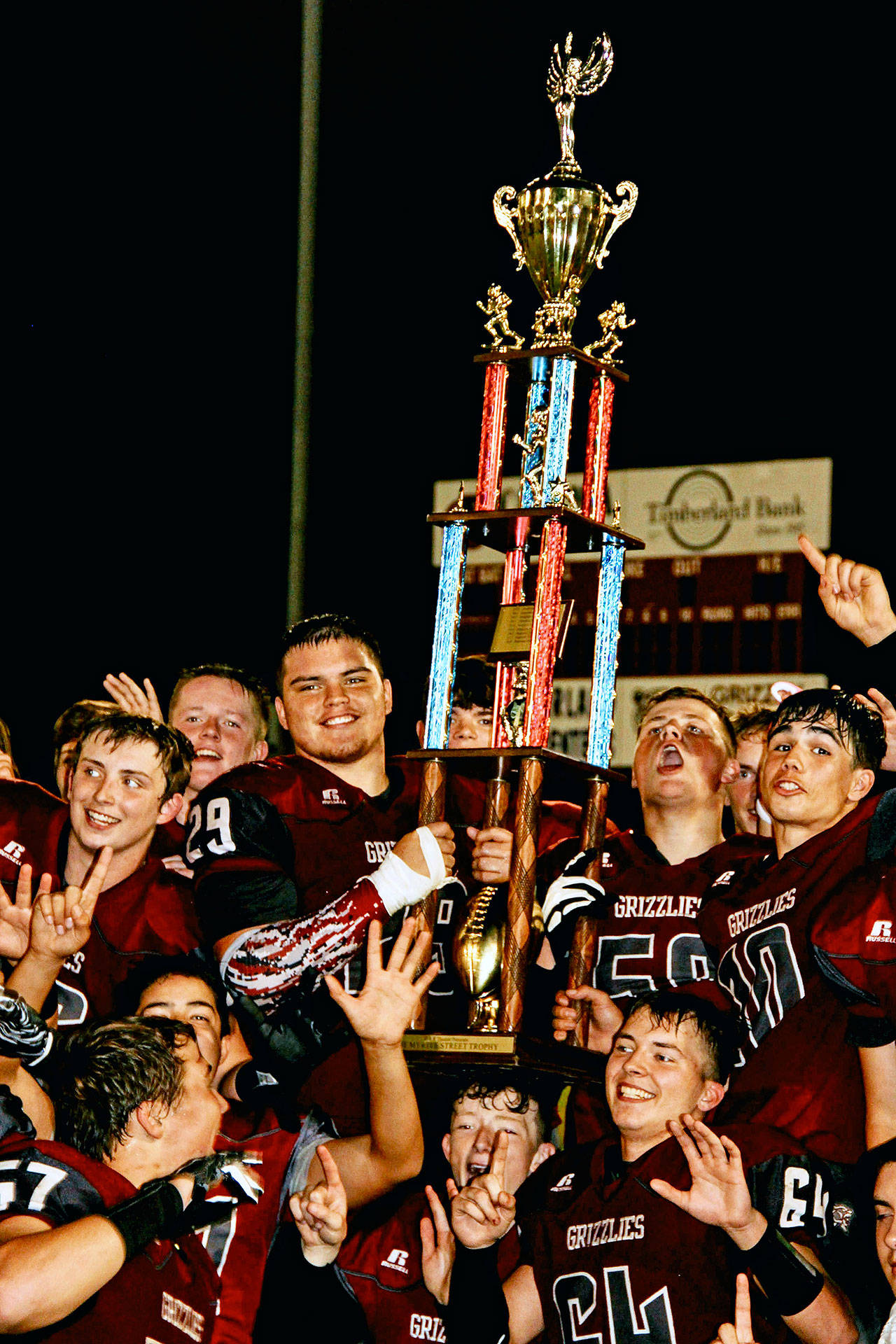 The Hoquiam Grizzlies hold up the Myrtle Street Rivalry trophy after defeating the Aberdeen Bobcats 56-3 on Friday, Sept. 13. Hoquiam has won 13 of its last 14 games dating back to last season and faces La Center on Friday. (Photo by Jinny Marchand)
