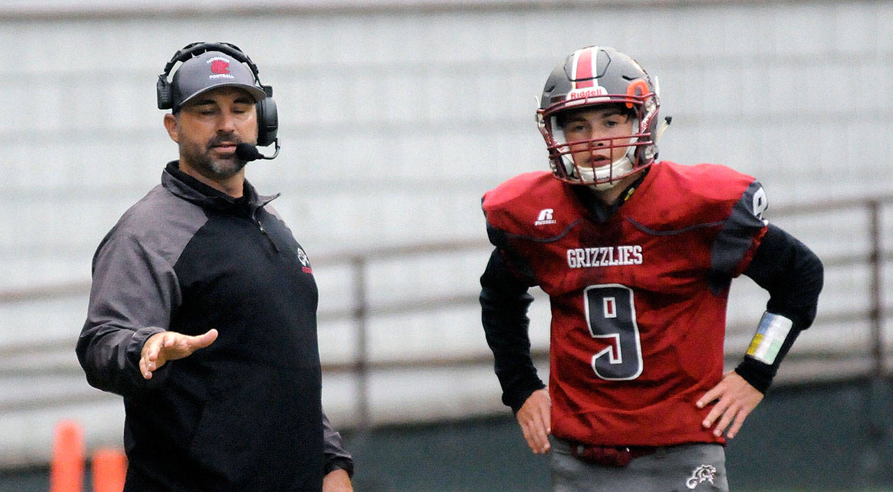 Hoquiam head coach Jeremy McMillan, left, strategizes with his son, Hoquiam quarterback Dane McMillan, during a game on Sept. 6 at Olympic Stadium. The Grizzlies how Columbia-White Salmon on Friday. (Ryan Sparks | Grays Harbor News Group)