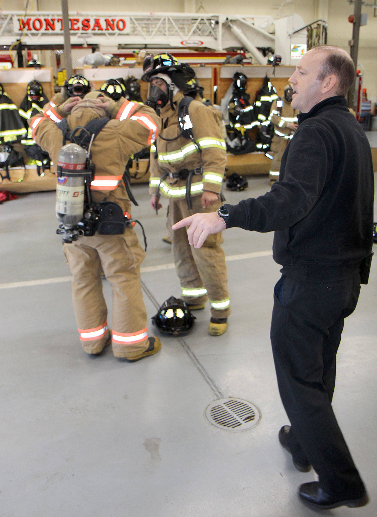Michael Lang | Grays Harbor News Group                                Montesano Fire Chief Corey Rux instructs his students Thursday, Oct. 10, at the Montesano Fire Station, while Montesano High School senior Cole Daniels helps a fellow fire science student put on bunker gear.