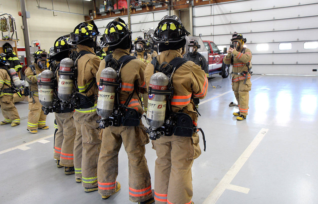 A group of students in the fire science class poses for a picture Thursday, Oct. 10, 2019, at the Montesanon Fire Station while a classmate takes the picture (right). (Michael Lang | Grays Harbor News Group)