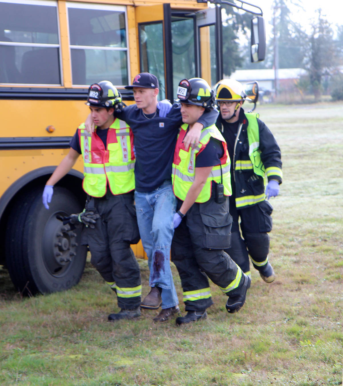 Michael Lang | Grays Harbor News Group                                First responders from multiple jurisdictions assist in evacuating an Elma High School student from a bus during an emergency preparedness drill for multiple emergency responder agencies Wednesday, Oct. 23, at the Grays Harbor County Fairgrounds in Elma. The student was pretending to have been injured during a roll over crash of the bus.