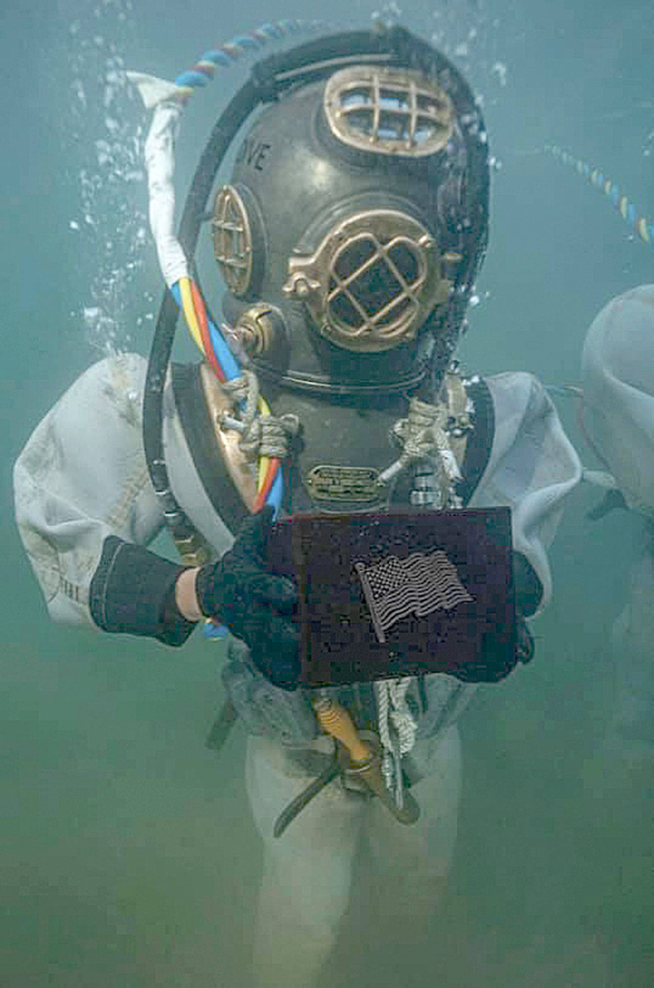 Photo courtesy U.S. Navy and Teri Mann Whyatt                                A U.S. Navy diver outfitted with 1940s era diving gear holds the remains of USS Arizona survivor and Elma High School graduate Lauren Bruner before placing the urn on the sunken ship. Bruner is the 44th and possibly last person whose remains will be added to the memorial in Pearl Harbor.