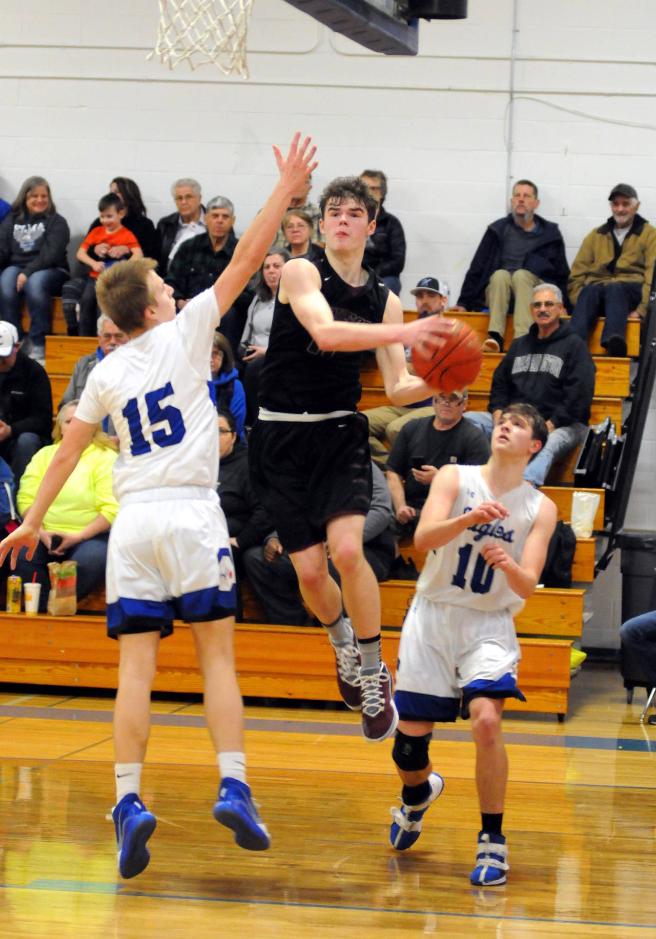 Montesano’s Wesley Bjornsgard drives to the basket while beind defended by Elma’s Brady Johnston (15) and Cobey Moore (10) during the Bulldogs’ 60-48 final on Wednesday in Elma. (Ryan Sparks | Grays Harbor News Group)