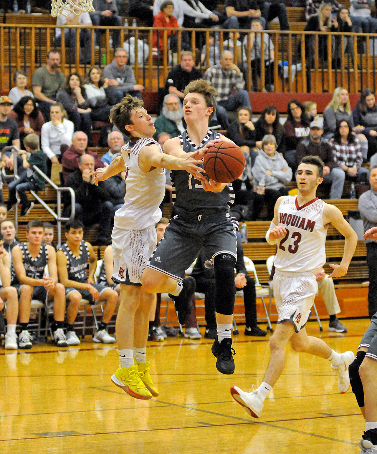 Montesano’s Carter Olsen, middle, drives to the basket against Hoquiam’s Cameron Bumstead during the Bulldogs’ 71-42 victory on Friday at Hoquiam High School. Olsen scored 20 points to lead all scorers. (Ryan Sparks | Grays Harbor News Group)