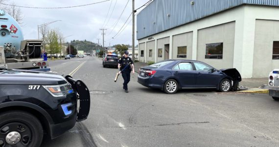 APD Patrol Officer Stephen Ayers carries a push broom to help him clear the debris from the 3-car collision Wednesday afternoon, May 18, at the intersection of South M Street and West State Street in Aberdeen. Matthew N. Wells | The Daily World