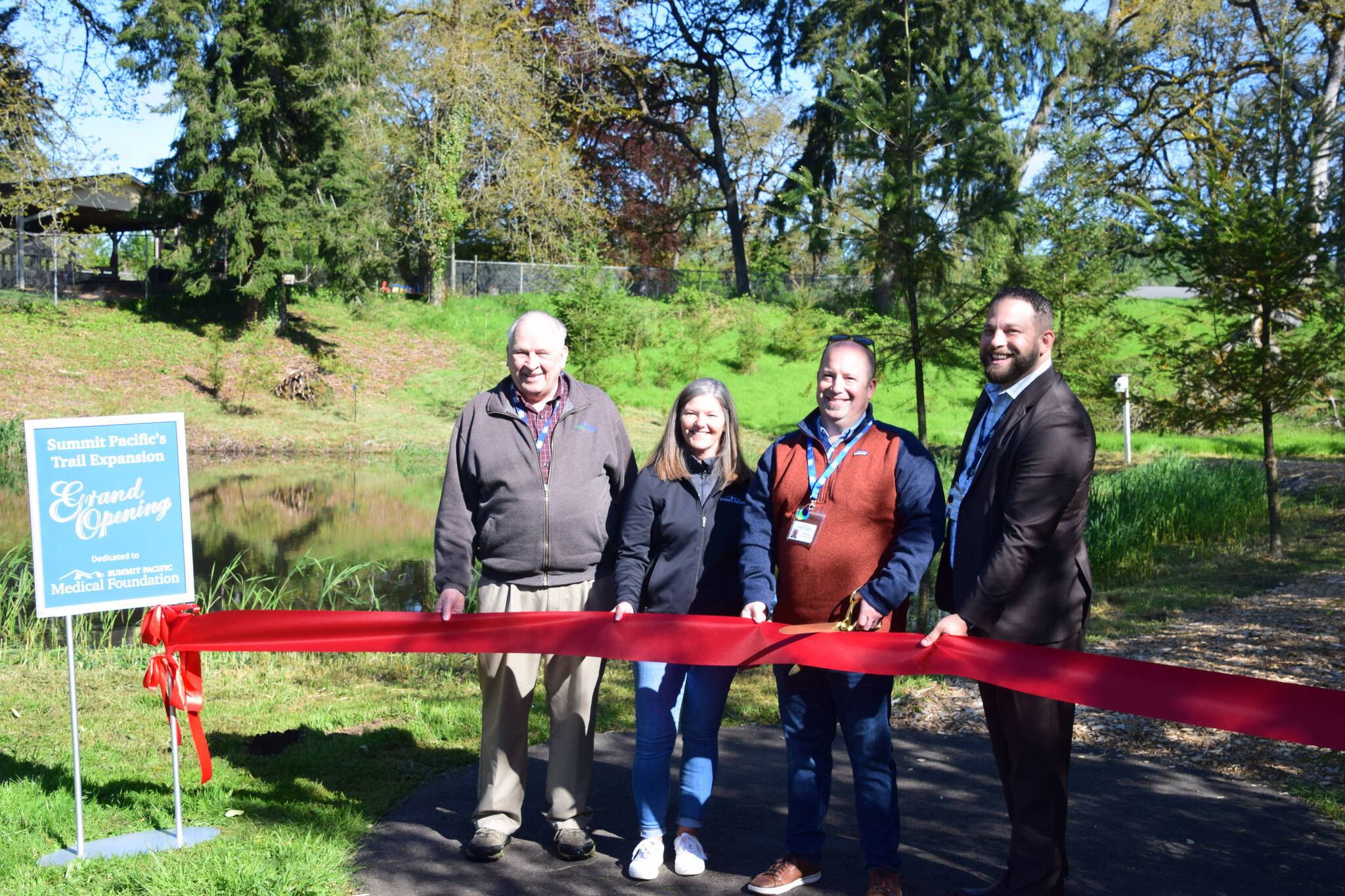 Summit Pacific Medical Foundation President Brian Smith (holding scissors) stands alongside foundation board members and Summit Pacific CEO Josh Martin (right) to celebrate the grand opening of the newest addition of the trail expansion at the hospital campus on May 20, 2022, in Elma. (Photo Courtesy of Nichole Pas)