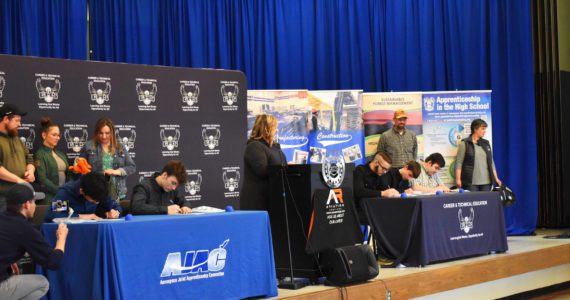 Allen Leister l The Daily World Students sign apprenticeship paperwork as their sponsoring company watches from behind during the AJAC Signing Ceremony at Elma High School on May 19, 2022, in Elma.