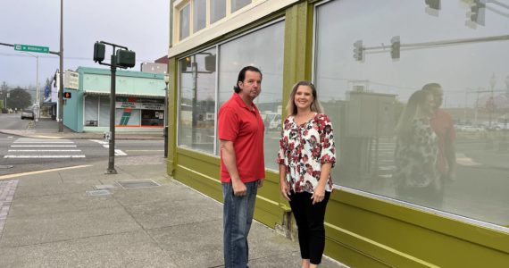 (Matthew N. Wells | The Daily World)
                                Lee Bacon and his wife Dani stand outside their building at the intersection of West Wishkah and South K streets. The 92-year-old urban moss green building used to house Goldberg’s Furniture. The couple, who spoke to The Daily World on Friday, Sept. 2, 2022, bought the building in April 2021. They have been working to restore and “revitalize” it since May 2021.