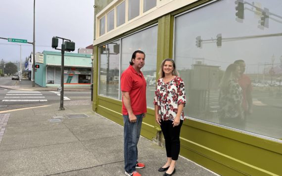 (Matthew N. Wells | The Daily World)
                                Lee Bacon and his wife Dani stand outside their building at the intersection of West Wishkah and South K streets. The 92-year-old urban moss green building used to house Goldberg’s Furniture. The couple, who spoke to The Daily World on Friday, Sept. 2, 2022, bought the building in April 2021. They have been working to restore and “revitalize” it since May 2021.