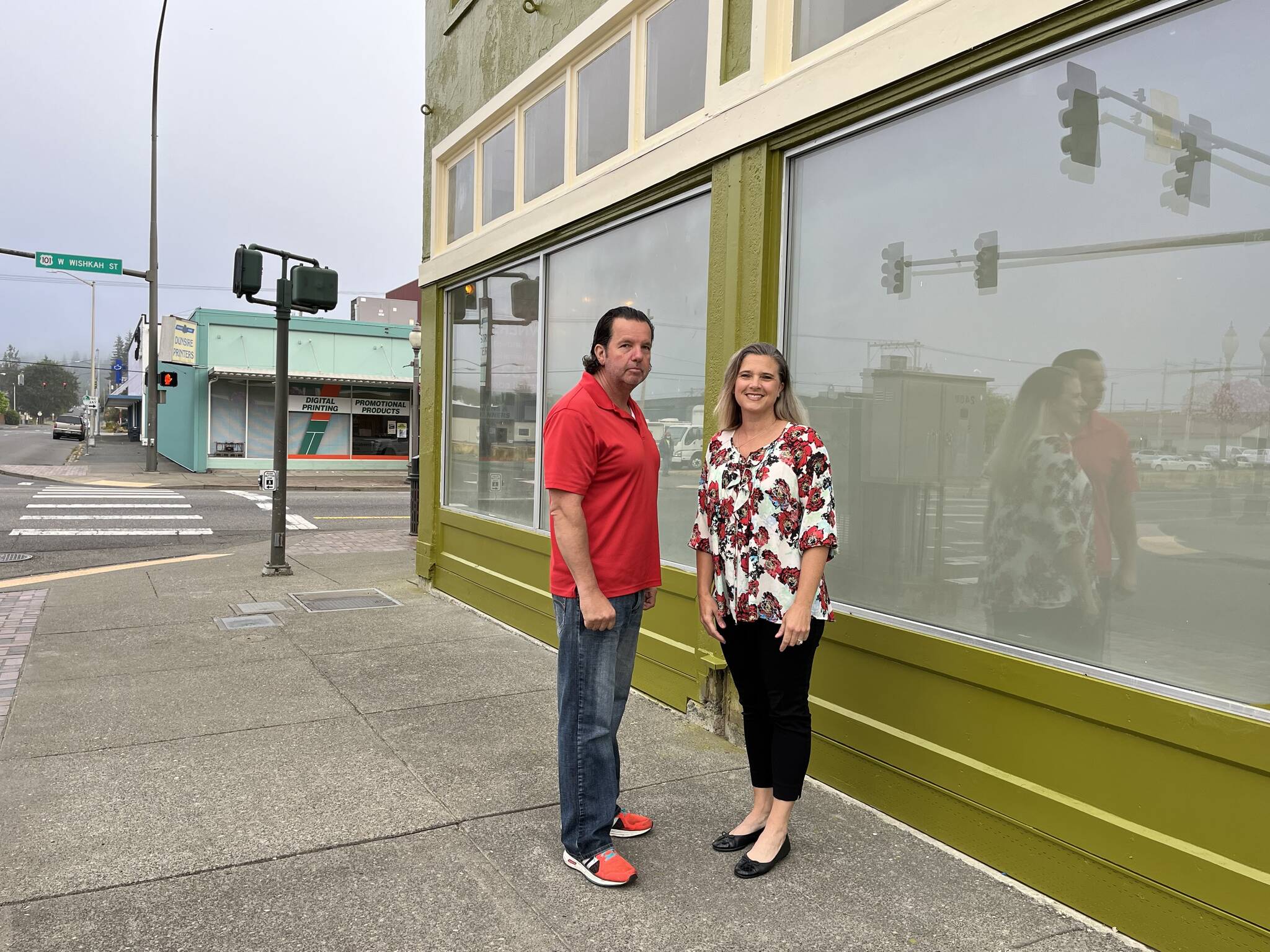 (Matthew N. Wells | The Daily World)
                                Lee Bacon and his wife Dani stand outside their building at the intersection of West Wishkah and South K streets. The 92-year-old urban moss green building used to house Goldberg’s Furniture. The couple, who spoke to The Daily World on Friday, Sept. 2, 2022, bought the building in April 2021. They have been working to restore and “revitalize” it since May 2021.