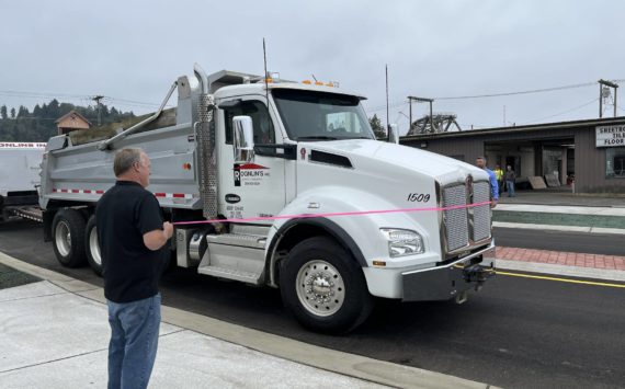 (Matthew N. Wells | The Daily World)
                                Aberdeen Mayor Pete Schave drives a Rognlin’s Inc. dump truck through the new roundabout just after 12 p.m., on Wednesday, Sept. 14. Rick Sangder, public works director for the city of Aberdeen, left, held the left end of the pink ribbon. City Engineer Nick Bird held the right end of the ribbon. The roundabout replaces the former five-way intersection of East Market Street, F Street and the one-way street, Fuller Way.